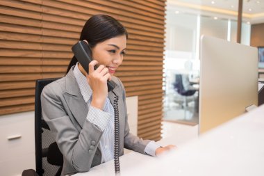 Vietnamese receptionist talking on telephone clipart