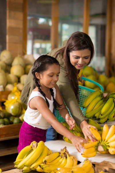 Mãe e filha escolhendo bananas maduras — Fotografia de Stock