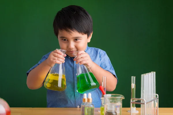 Chłopiec wącha kolorowy płyn w kolbach — Zdjęcie stockowe