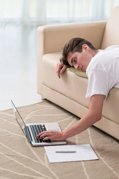 Homem deitado no sofá e usando laptop — Fotografia de Stock