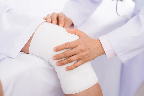 Orthopedist examining twisted knee — Stock Photo, Image