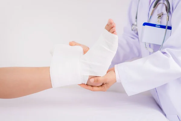 Doctor bandaging foot of a patient — Stock Photo, Image