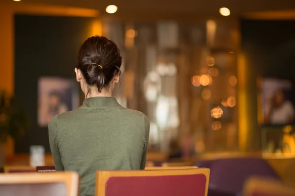 Женщина с непринужденной прической сидит в кафе — стоковое фото