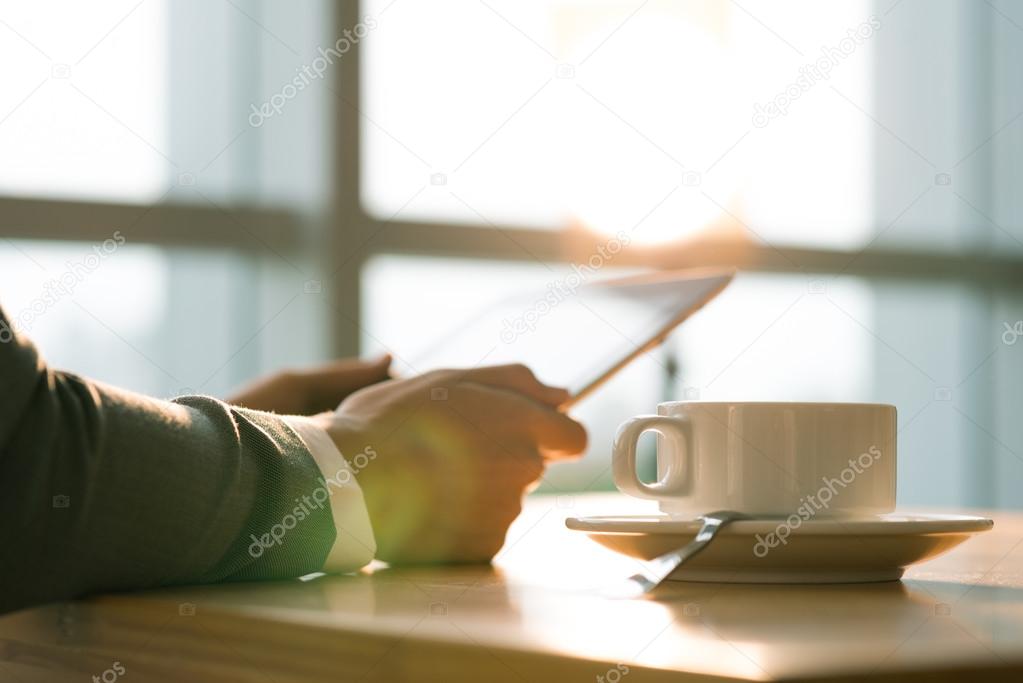 person drinking coffee and reading news