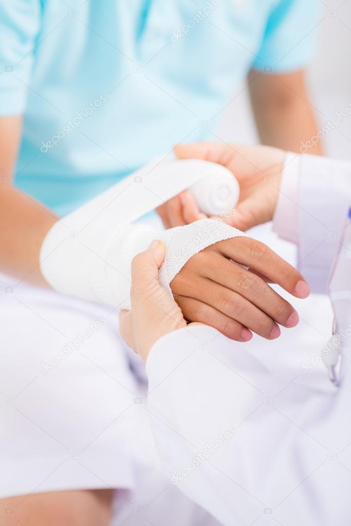 Doctor bandaging wrist of the patient