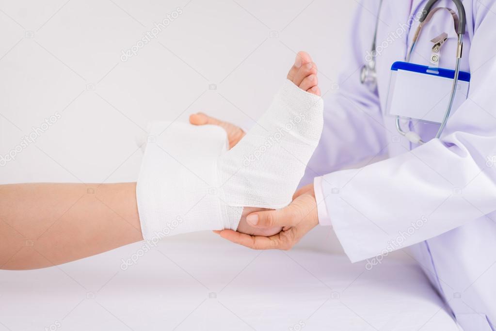 doctor bandaging foot of a patient