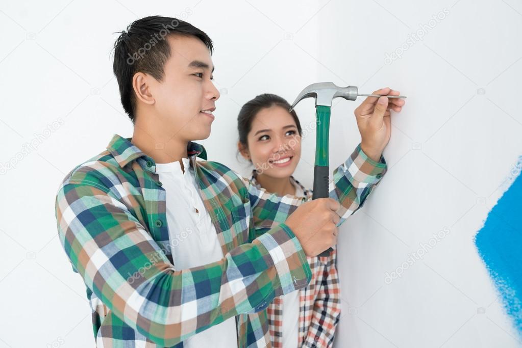man riving nail into wall