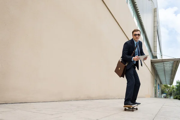 Podnikatel s počítačem skateboardu podél ulice — Stock fotografie
