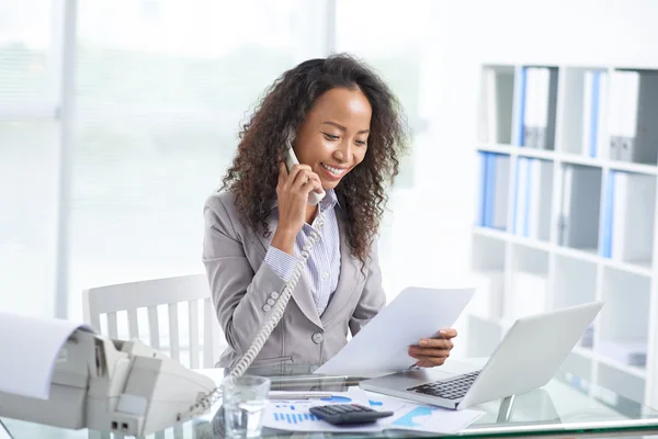 Businesswoman reading document and talking on phone — Stock Photo, Image