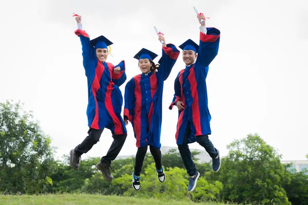 Прыгающие молодые выпускники — стоковое фото