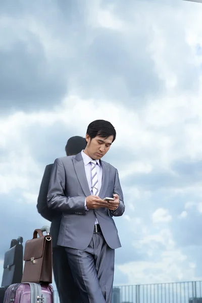 Enviar mensajes de texto a un hombre de negocios con equipaje — Foto de Stock