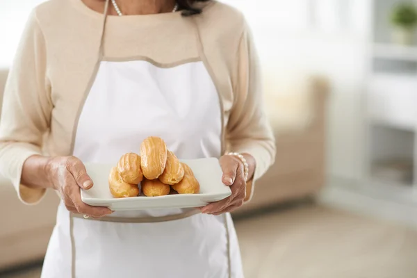 Woman with freshly baked eclairs — Stock Photo, Image
