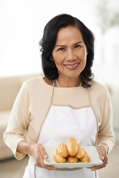 Asiática senior mujer ofreciendo pasteles —  Fotos de Stock