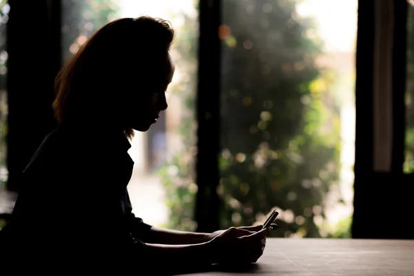 Silhouette einer Frau, die SMS liest — Stockfoto