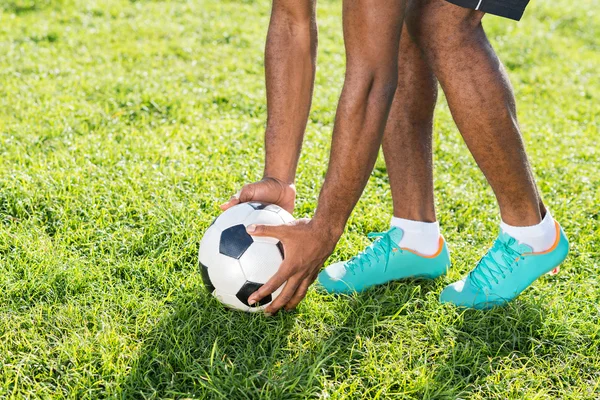 Frente colocando bola de futebol na grama — Fotografia de Stock