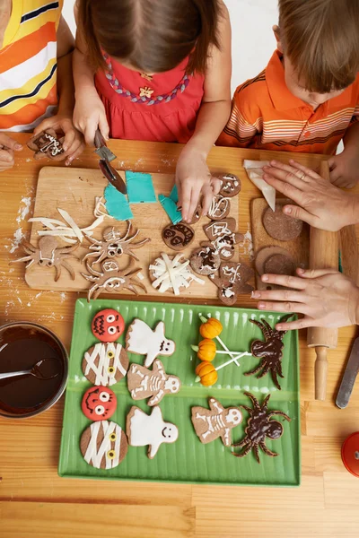 Moeder en kinderen versieren Halloween cookies — Stockfoto