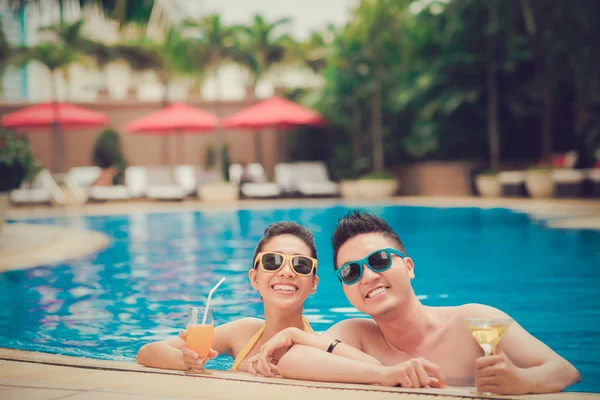 Pareja feliz en gafas de sol en la piscina —  Fotos de Stock