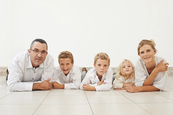 Familia alegre tendida en el suelo — Foto de Stock