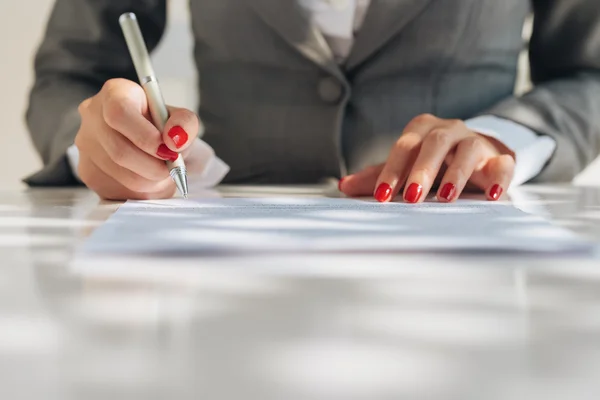 Female manicured hands signing a document — Stock Photo, Image