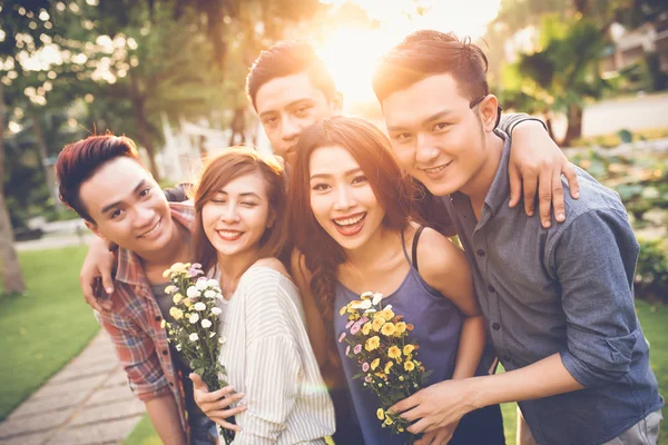 Amici allegri in posa con i fiori — Foto Stock