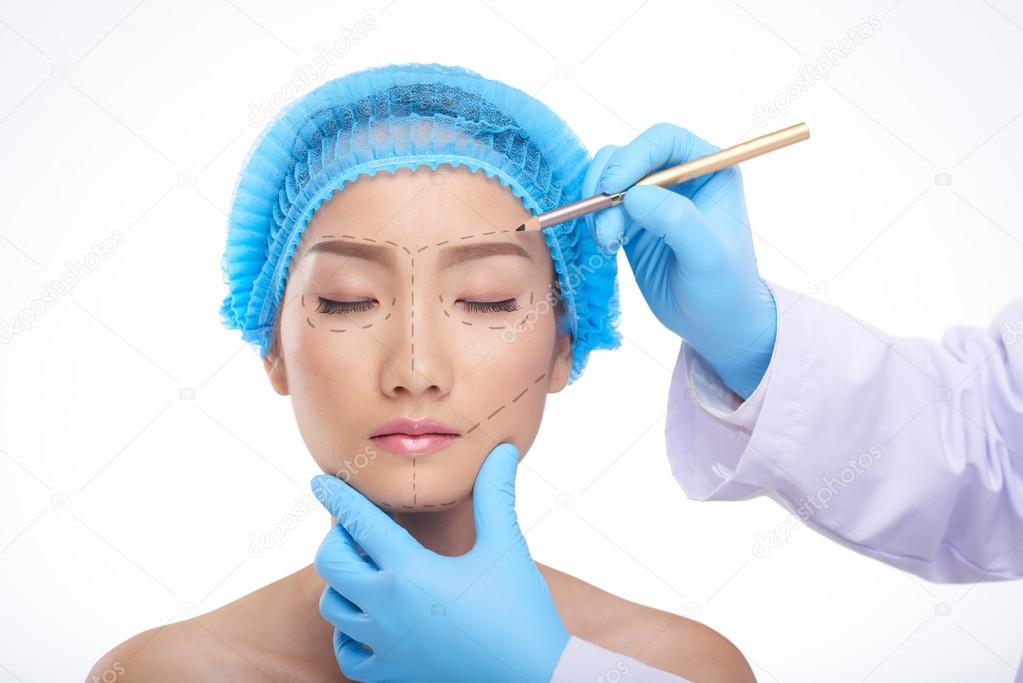 Doctor drawing perforation lines on face