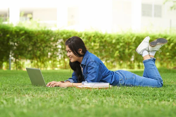 学生は草の上に横たわるとラップトップを使用して — ストック写真