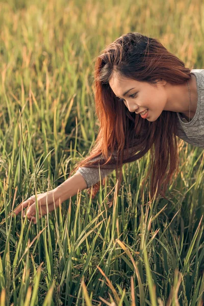 Docela usměvavá žena dotýká trávy — Stock fotografie