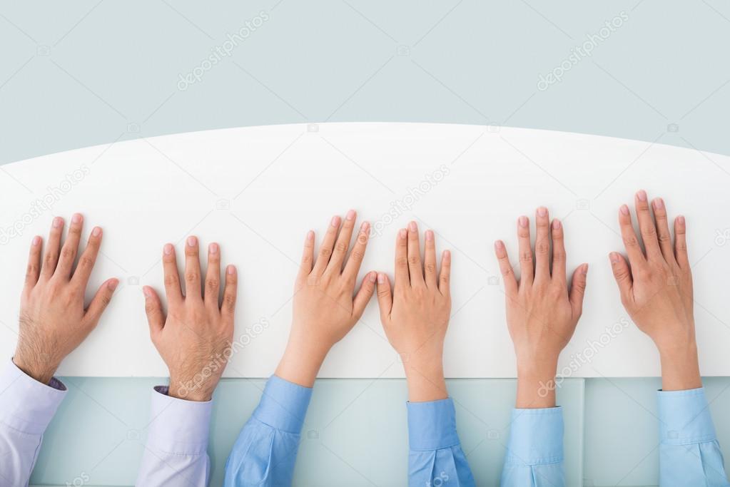 Row of hands on desk