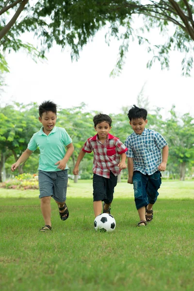Возбужденные школьники играют в футбол — стоковое фото
