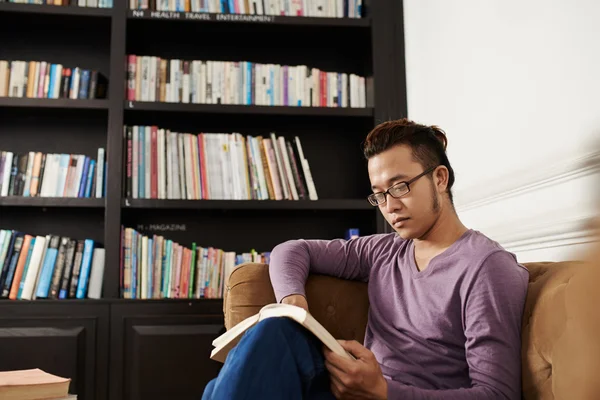 Человек, читающий роман в библиотеке — стоковое фото