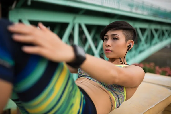 Asiatisk tjej gör sit-ups utomhus — Stockfoto