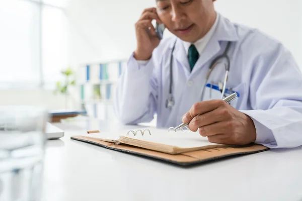 Médico falando e fazendo anotações — Fotografia de Stock