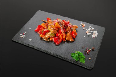 Sebzeli ve ekşi soslu domuz eti. Siyah bir tahta üzerinde. Karanlık arka plan. İzole edilmiş