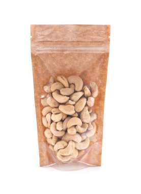 Kahverengi bir kese kağıdında kaju fıstığı. Toptan ürünler için plastik pencereli bir paket. Yakın plan. Beyaz arka plan. İzole edilmiş.