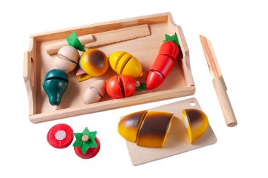 Sebze doğrarız. Sebzeli tepsi ve tahta oyuncaktan yapılmış iki bıçak Montessori. Beyaz arka plan. Yakın plan..