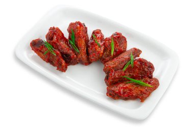 Barbekü soslu tavuk kapağı ve yeşil soğan. Beyaz dikdörtgen seramik bir tabakta. Beyaz arka plan. İzole edilmiş.