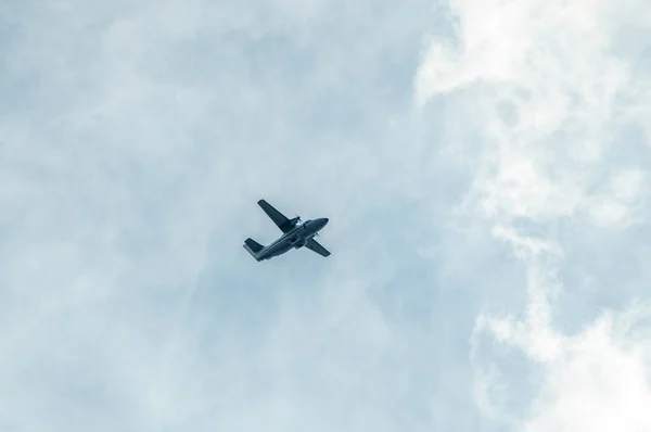 the plane flies in the cloudy sky