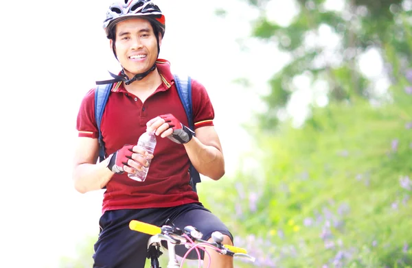 Happy man cyclist resting holding water bottle — Stock Photo, Image