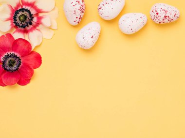 Minimalist Paskalya Tatili şablonu sarı tonlu, şakayıklı, kırmızı ve beyaz yumurtalı. Üst görünüm, metin için boşluk.