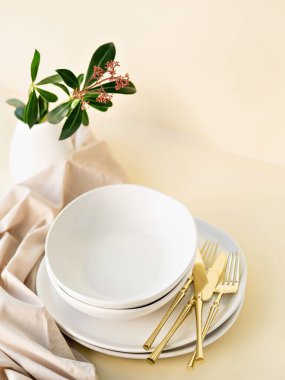 Altın çatal bıçak setiyle gün ışığında boş çanak çömlek seti. Bej ve dünyevi renkler. El yapımı seramik, çömlek, restoran veya yemek konsepti. Boşluğu kopyala.