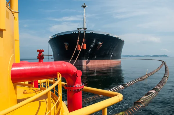 Oil tanker is transferring oil to the cargo vessel