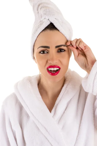 Schöne Frau im Bademantel zupft Augenbrauen — Stockfoto