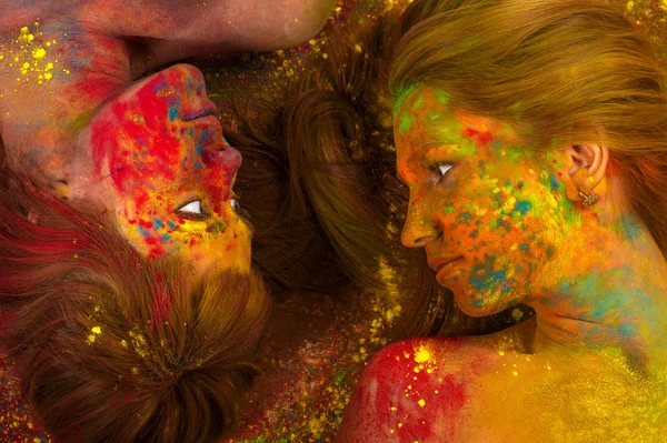 Two beautiful women lying on the floor in the colors of Holi — Stock Photo, Image