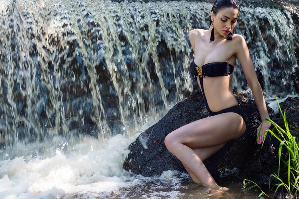 Seductive woman in black swimsuit on background waterfall — Stock Photo, Image