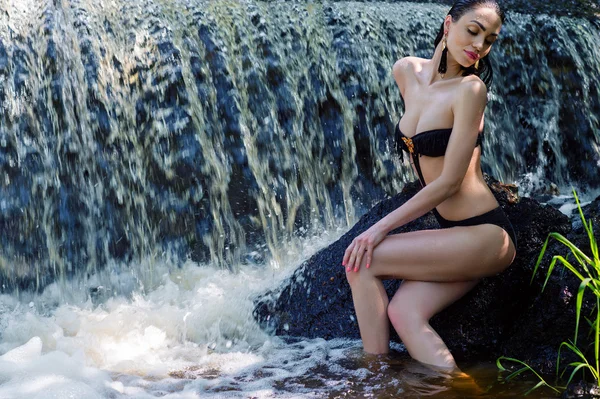 Elegant woman in black swimsuit on background waterfall — Stock Photo, Image