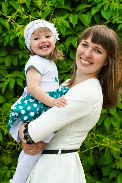 Glückliche Mutter mit einer Tochter an den Händen, die lächelt — Stockfoto