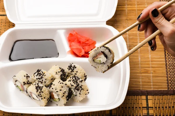 Kobieta trzyma pałeczki do sushi roll — Zdjęcie stockowe