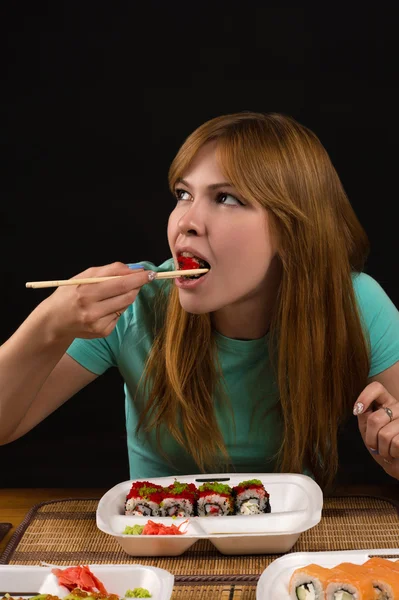 Aantrekkelijk meisje broodjes eten aan de tafel — Stockfoto