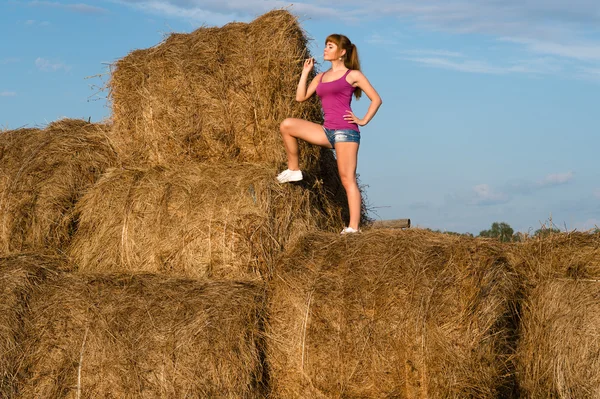 Young woman standing on top of haystacks — Stock Photo, Image