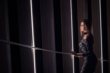 Gece elbisesi giymiş zarif bir kadın merdivenlerde dikiliyor. 